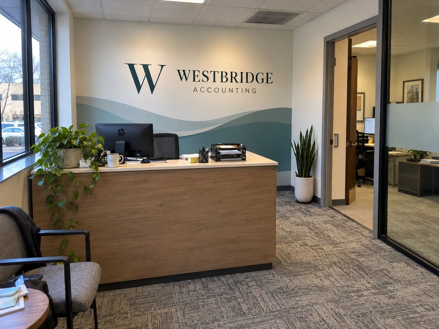 Office reception with a teal wave wall graphic, dimensional company lettering and frosted glass partitions